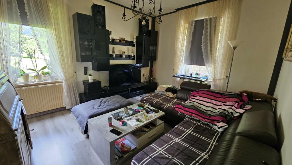 Wohnzimmer mit Couch, Fernseher und Kaminofen in Österreich