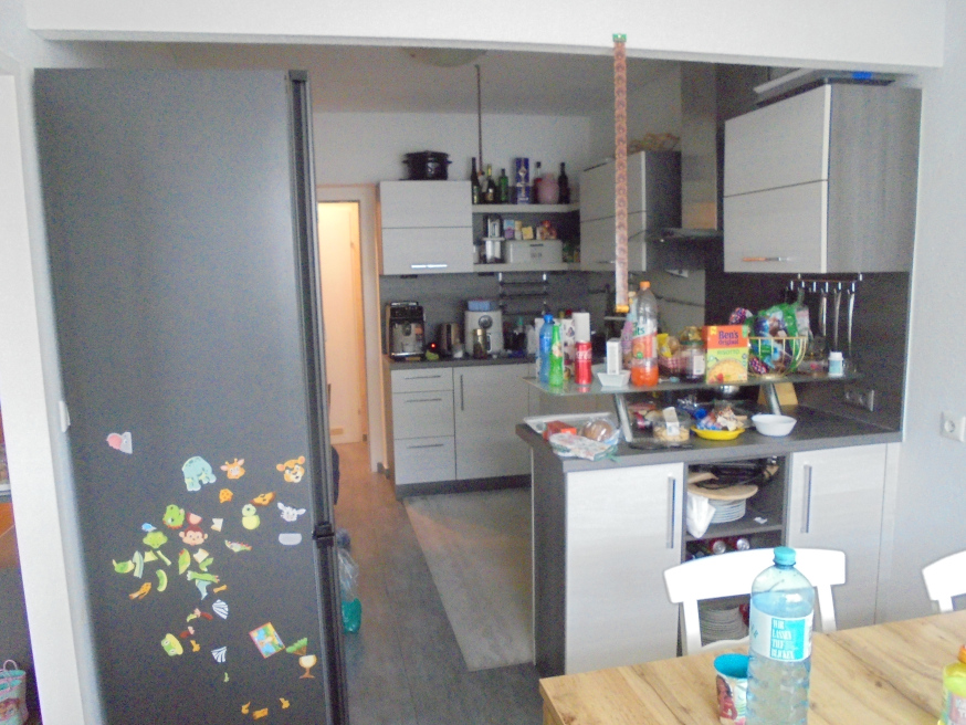 Küche mit Kühlschrank und Küchenzeile, gefüllt mit Lebensmitteln.
