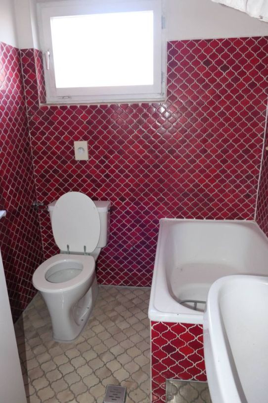 Badezimmer mit roter Mosaikwand, Fenster, Toilette und Badewanne