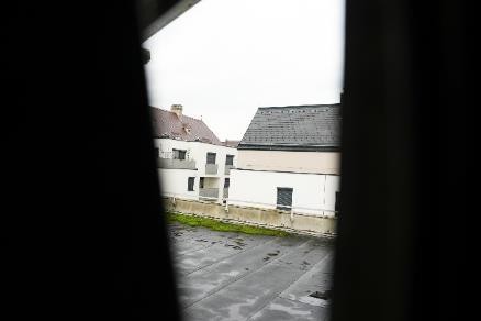 Gebäude in Österreich mit Flachdach und Satteldach, von dunklen Vorhängen eingerahmt