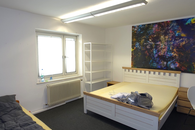Schlafzimmer mit Bett, Regal, großem Bild und Fenster