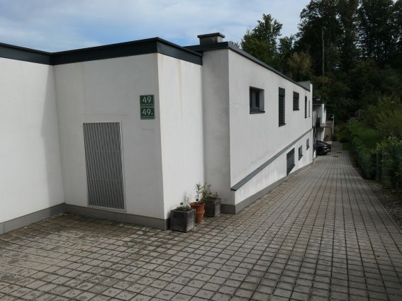 Modernes Haus mit Hausnummer 49 in Wien, Einfahrt mit Steinplatten und Bäumen
