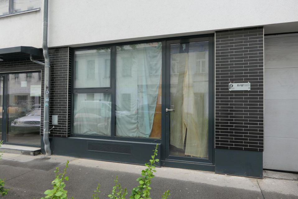 Gebäudefront mit dunkler Klinkerfassade und großen Fenstern mit Vorhängen