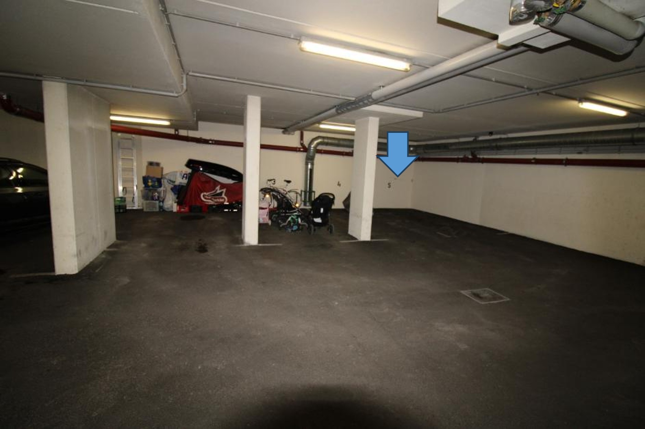 Tiefgarage mit Kinderwagen, Fahrrädern und abgestelltem Autozubehör.
