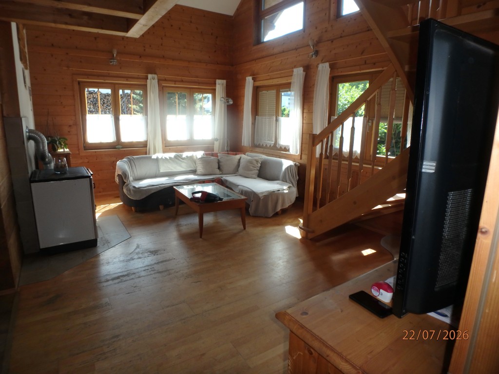 Wohnzimmer mit Holzverkleidung, Kachelofen, Eckcouch und Treppe