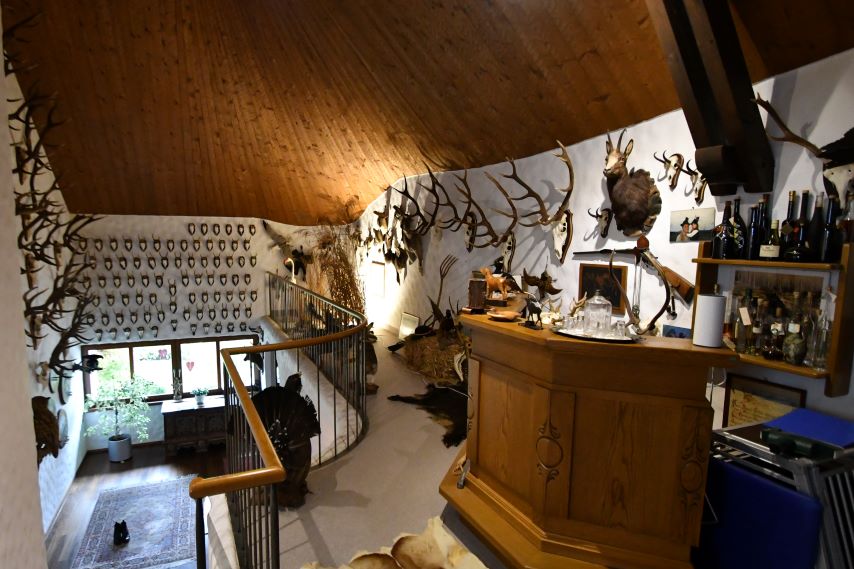 Jagdzimmer mit Geweihen, Jagdtrophäen und einer Bar