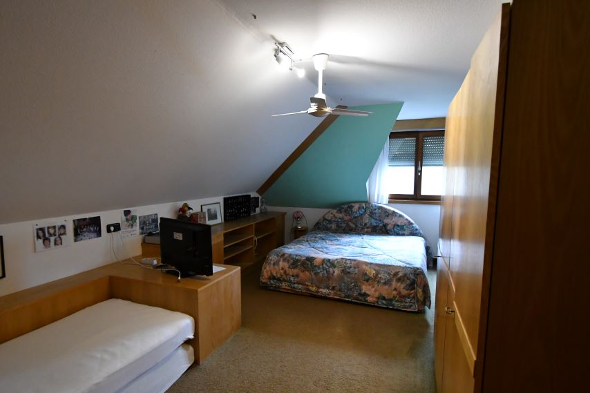 Schlafzimmer mit Doppelbett, Einzelbett und Fernseher im Dachgeschoss.