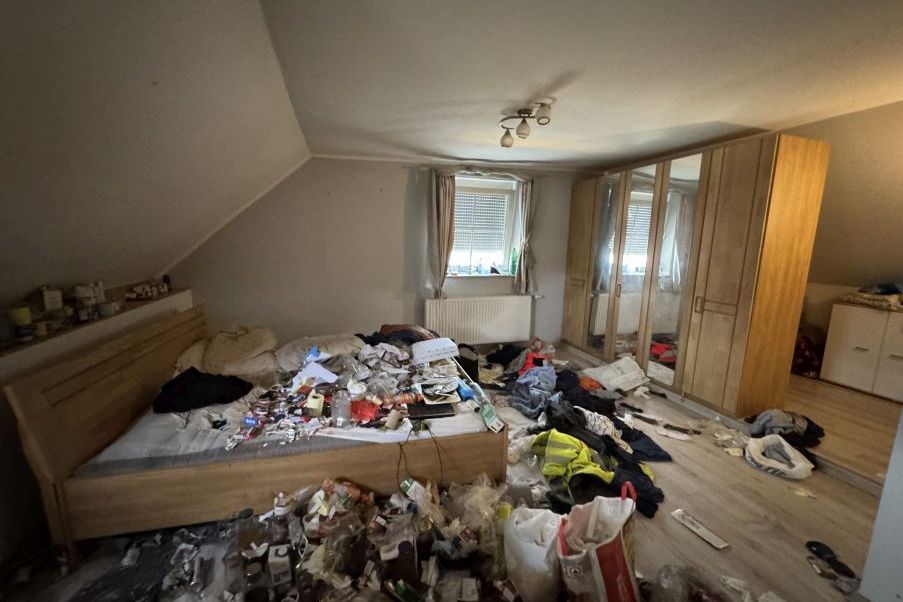 Unordnung in Schlafzimmer mit Bett, Kleiderschrank und vielen herumliegenden Gegenständen