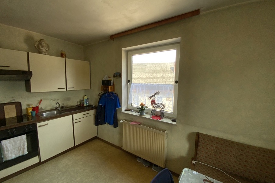Küche mit Einbauküche, Herd und Fenster mit Dekoration.