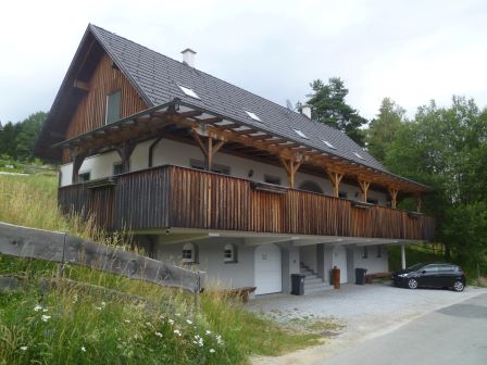 Holzhaus mit Balkon und Parkplatz in ländlicher Umgebung