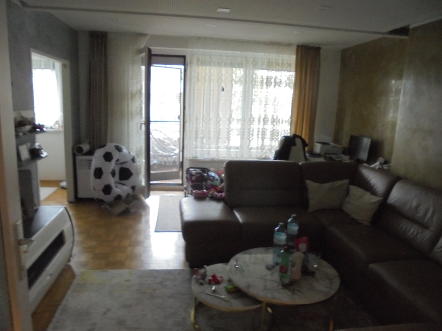 Wohnzimmer mit brauner Ledercouch, Couchtisch mit Flaschen und ein aufblasbarer Fußball