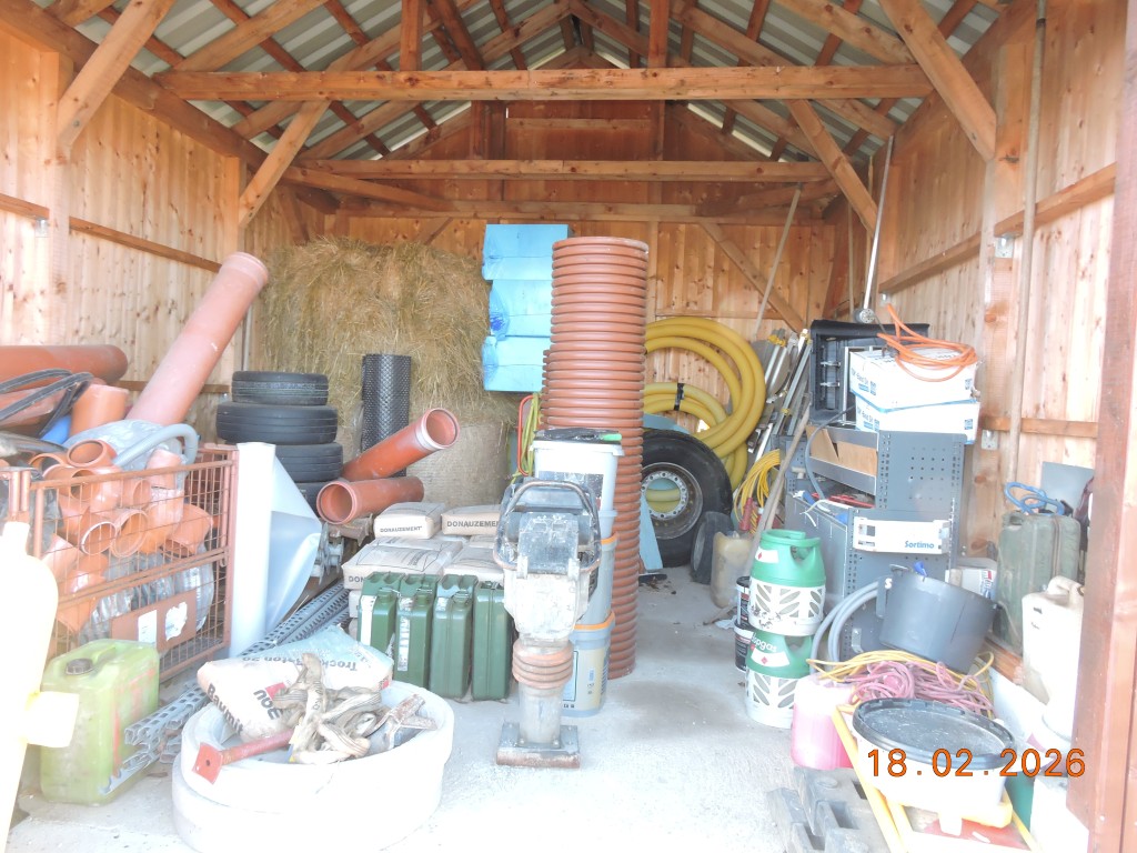 Lagerhalle mit Baumaterialien, Rohren, Heuballen und Werkzeugen