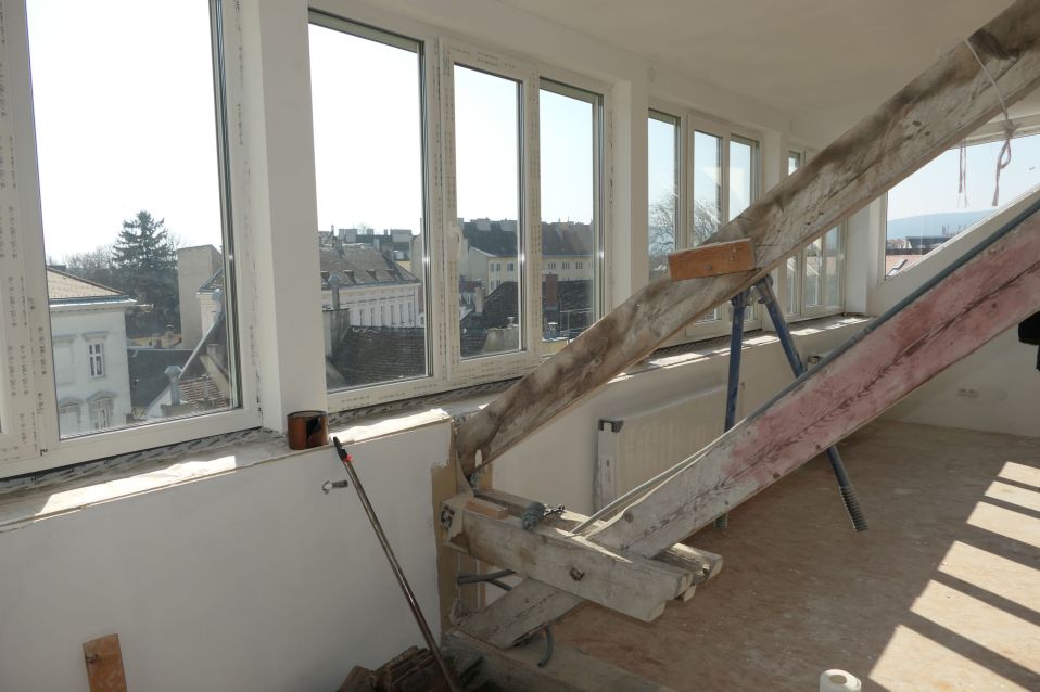 Baugerüst mit Holzbalken vor Fenstern mit Blick auf Grazer Altstadt