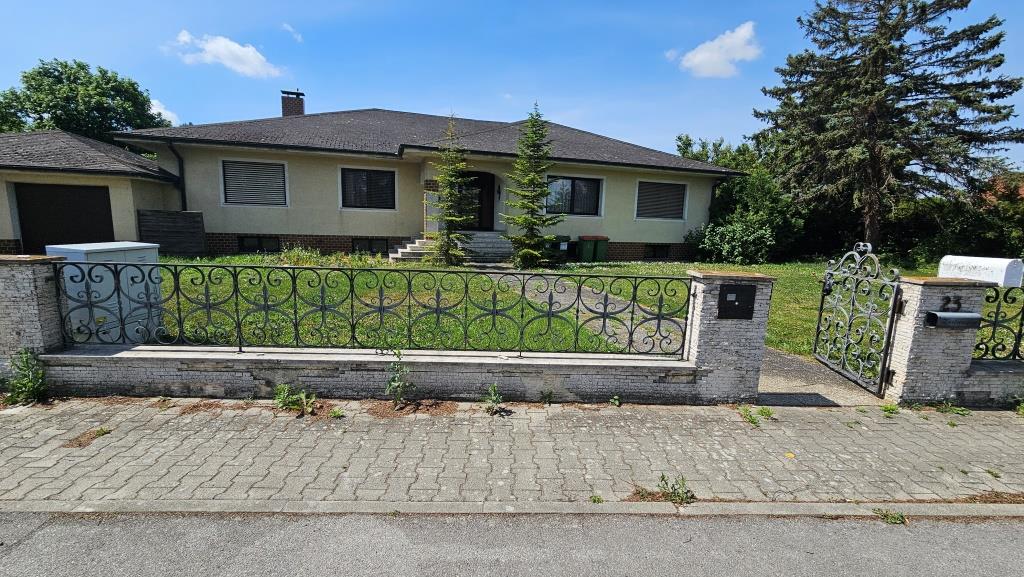 Einfamilienhaus mit Garage, schmiedeeisernem Zaun und offenem Tor in Österreich