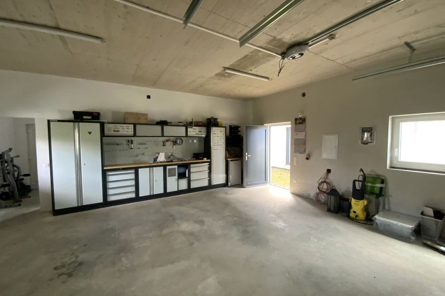 Werkstatt mit Werkbänken, Schränken und Werkzeugwand, Garagentor, Fenster