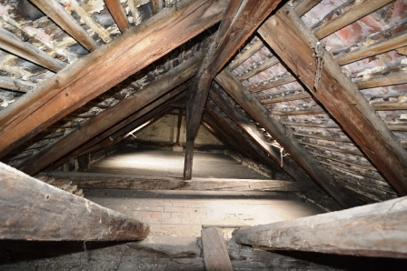 Dachboden mit Holzbalken und Ziegelwänden, in einem alten Haus