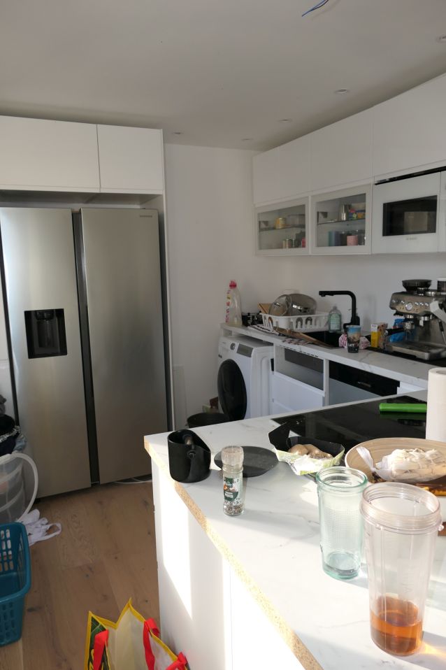 Küche mit Kühlschrank, Waschmaschine, Kaffeemaschine und Küchenutensilien