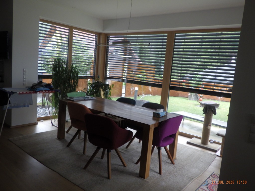 Esszimmer mit Holztisch, vier Sesseln und Blick in den Garten.