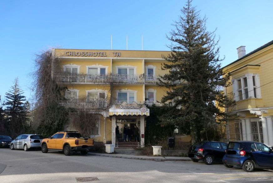 Schlosshotel Th in Bad Ischl mit gelber Fassade und Autos davor.