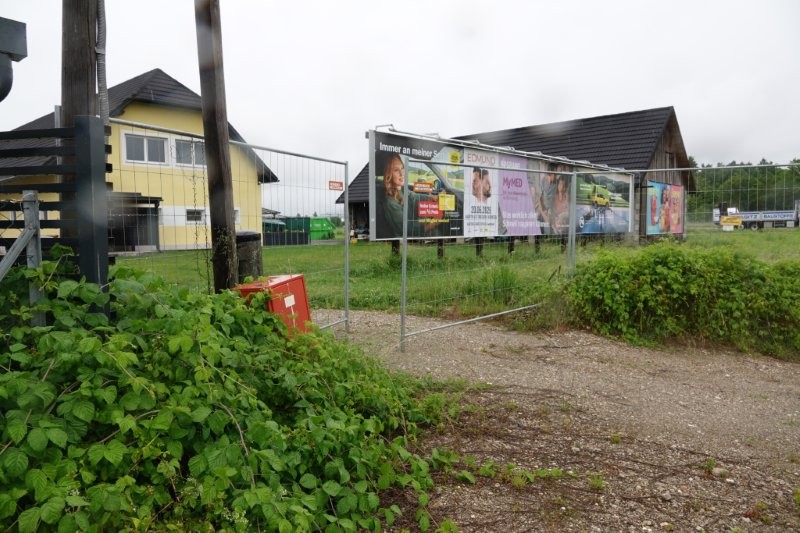 Werbeplakate mit Frauen und Männern vor einem gelben Haus und Holzhütte in Österreich.