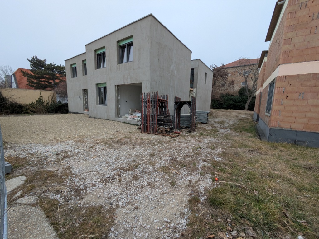 Neubau in Wien: Zwei Rohbauten, einer verputzt, einer Ziegelbau, mit Gerüst im Freien