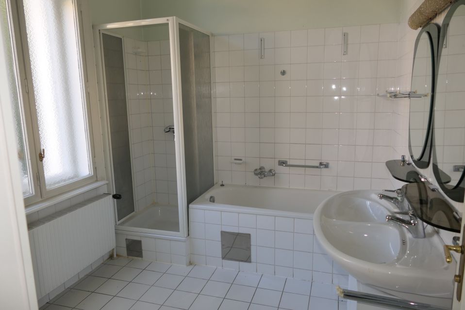 Badezimmer mit Dusche, Wanne, Waschbecken und Spiegel