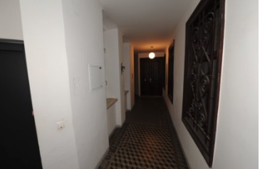 Gang mit dunklen Türen, Kachelboden und Ziergitter in Wien