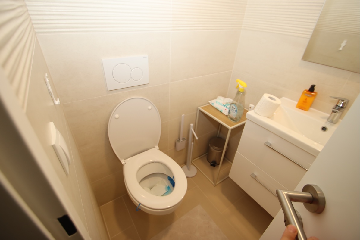Toilette, Waschbecken und Badezimmermöbel in einem hellen Raum