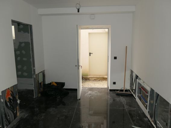Baustelle mit offenen Wänden und Rohren, Besen und Müllsack