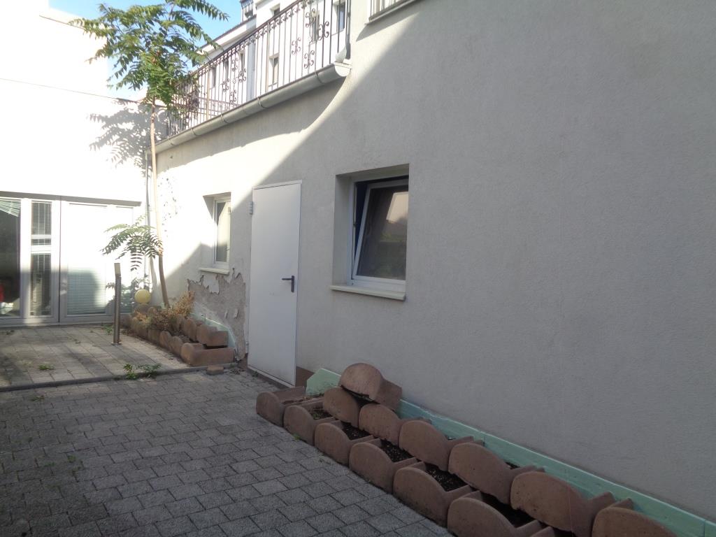 Hof mit Pflastersteinen, einer weißen Tür, einem Fenster und einem Baum