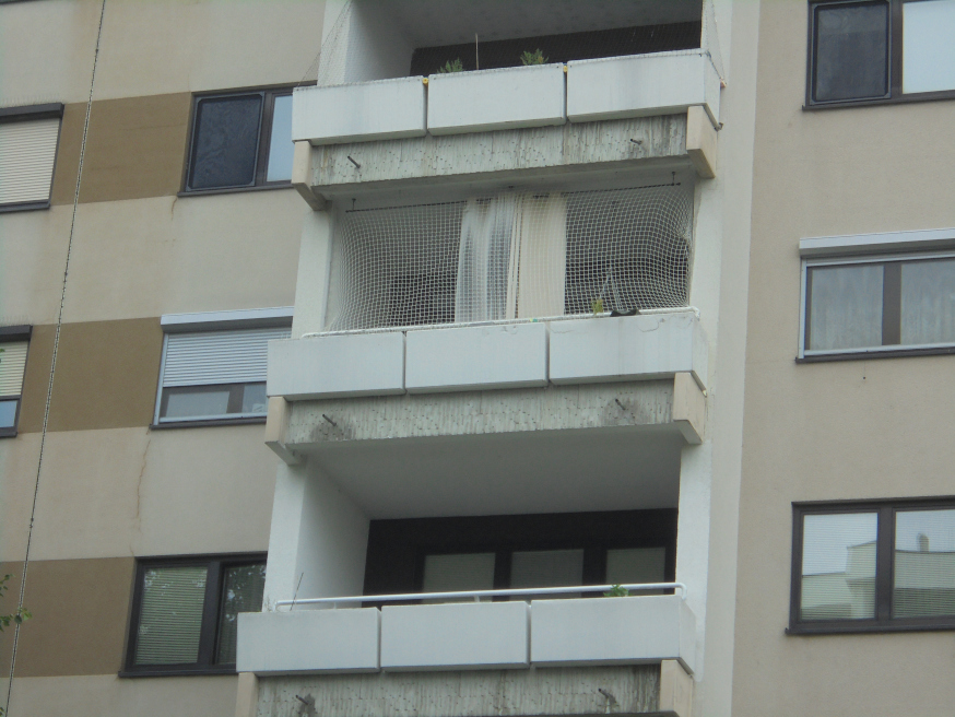 Balkone mit Gittern und Fenster an Wohnhausfassade in Wien