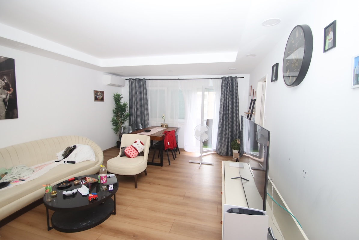 Wohnzimmer mit Sofa, Essbereich, Fernseher und Bildern an der Wand