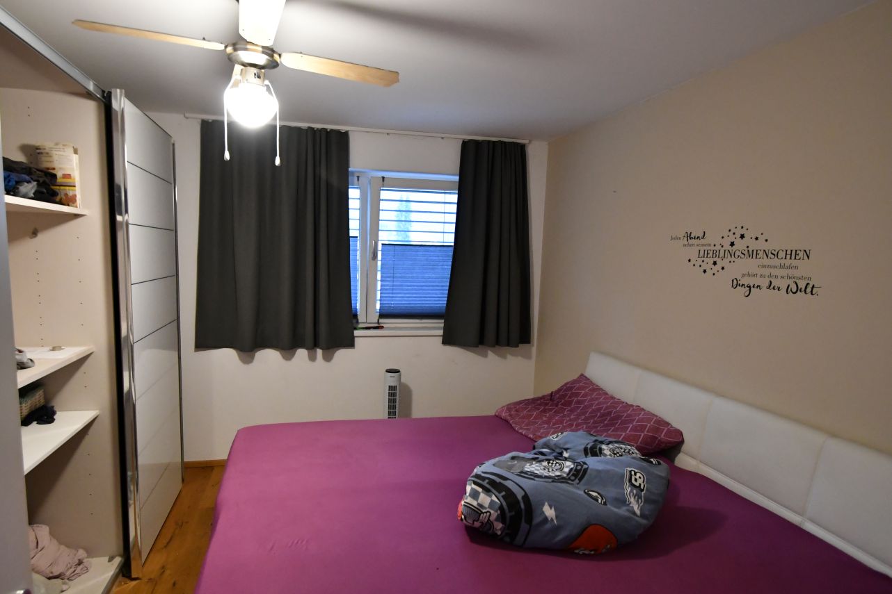 Schlafzimmer mit Deckenventilator, Kleiderschrank, Bett und Wandspruch