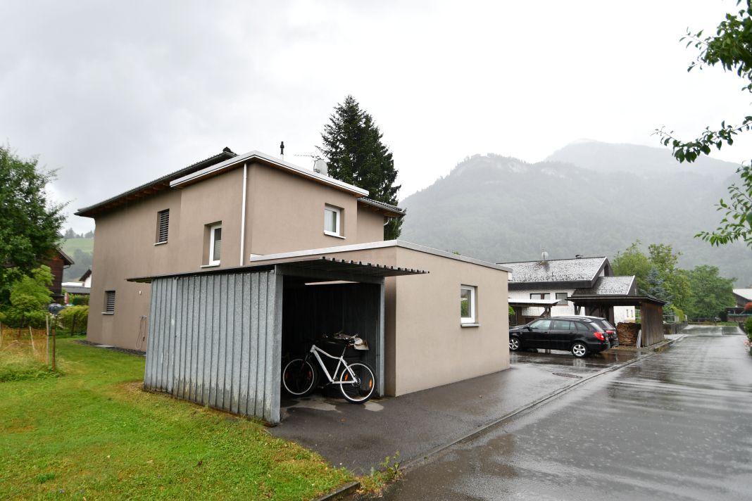 Zwei Fahrräder stehen unter einem Carport vor einem Einfamilienhaus in den Alpen.