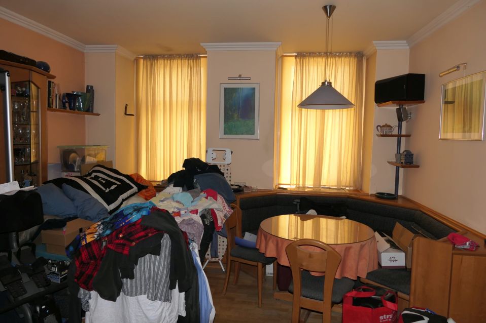 Unaufgeräumtes Wohnzimmer mit Kleidung und Möbeln in Österreich