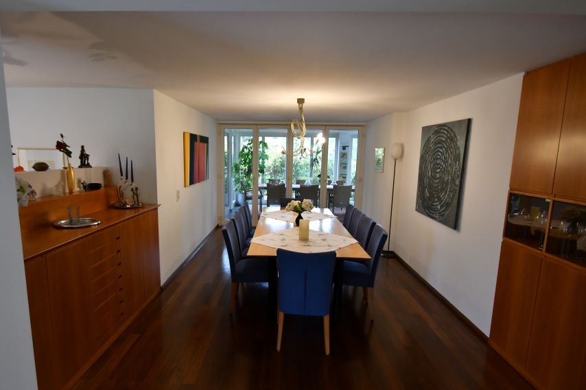 Esszimmer mit langem Holztisch, blauen Stühlen und Glasfront nach draußen