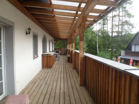 Holzterrasse mit Überdachung und Blick auf Bäume und ein Haus in Österreich