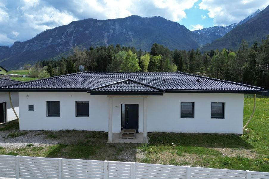 Neubau Einfamilienhaus mit dunklem Ziegeldach und Bergkulisse in Österreich
