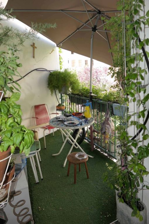 Balkon mit Tisch, Stühlen und Pflanzen unter Sonnenschirm in Wien