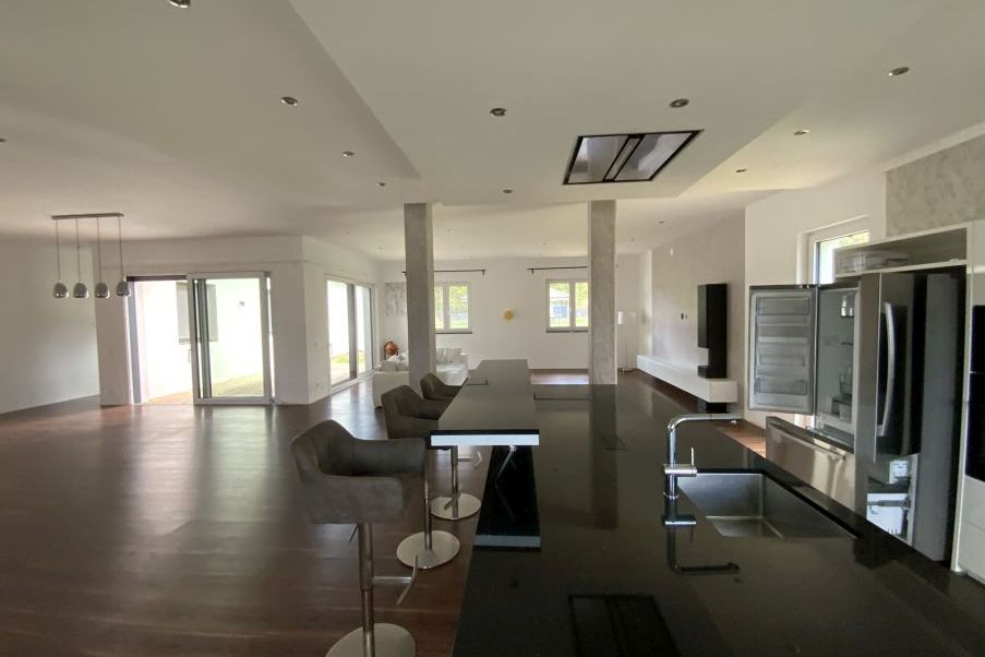 Moderne Küche mit Kochinsel, Kühlschrank und Essbereich in hellem, offenem Wohnraum