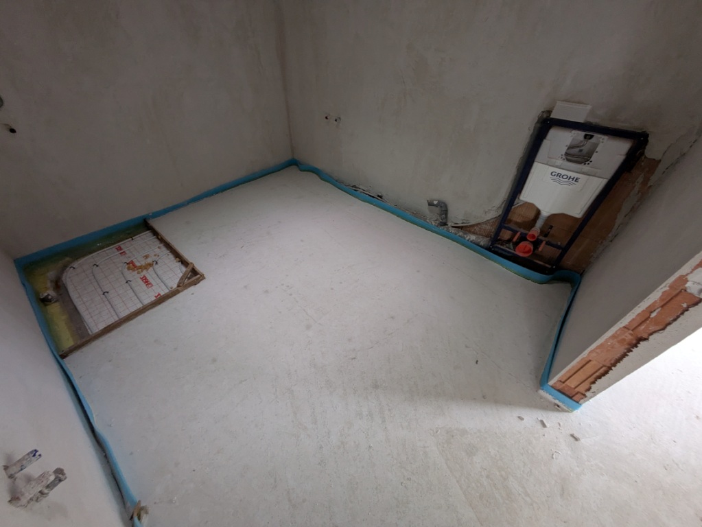 Fußbodenheizung und Geberit-Spülkasten in einem Rohbauzimmer