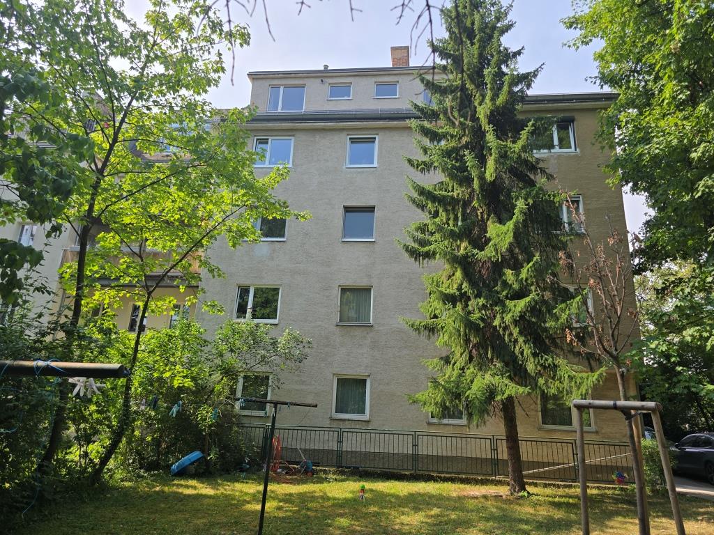 Mehrfamilienhaus mit Bäumen und Spielplatz im Hof