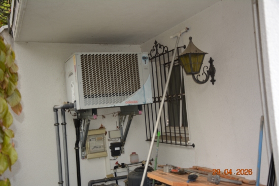 Heizungspumpe mit Rohrleitungen und Sicherungskasten an einer Hauswand in Österreich