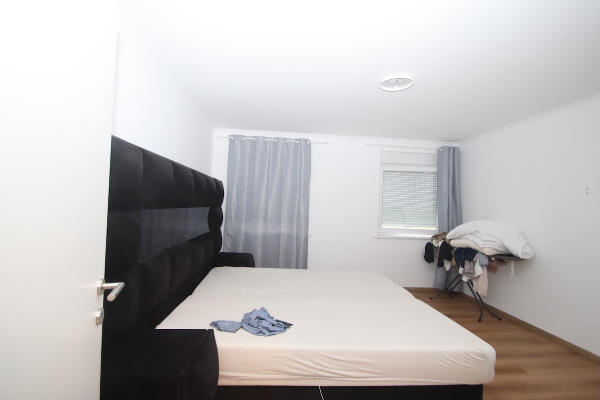 Schlafzimmer mit Doppelbett, Wäscheständer und Gardinen