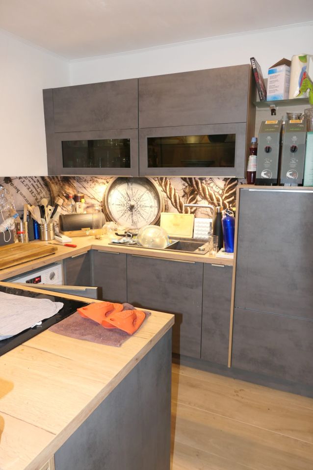 Küche mit Kompass-Motiv an der Wand und grauen Schränken