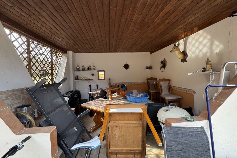 Gartenzimmer mit Holzdach, Jagdtrophäe, Esstisch und Sitzgelegenheiten