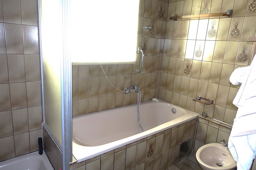 Badezimmer mit Badewanne, Duschwand und Bidet, gefliest