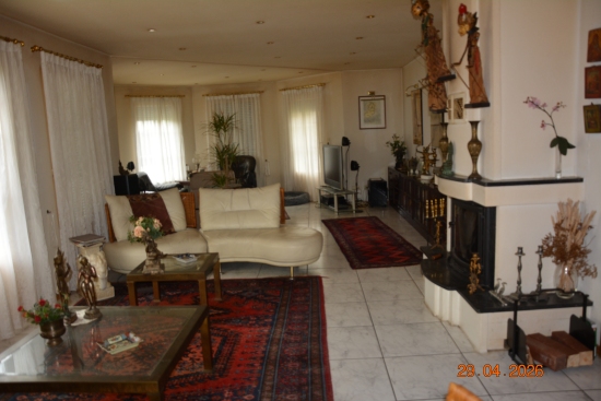 Wohnzimmer mit weißem Ledersofa, zwei Couchtischen und Kamin
