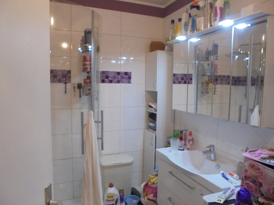 Badezimmer mit Dusche, Waschbecken und Spiegelschrank, gefliest