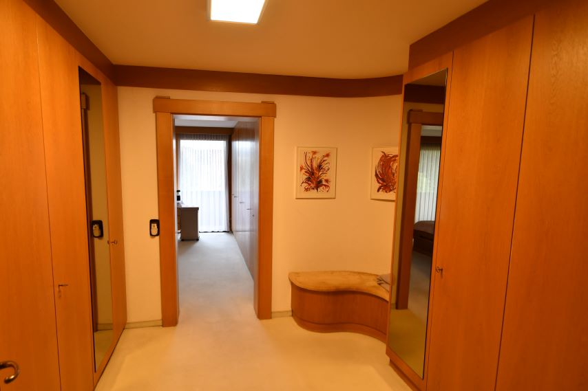 Garderobe mit Spiegeln und zwei Bildern an der Wand, Sitzbank und Durchgang in ein Zimmer.